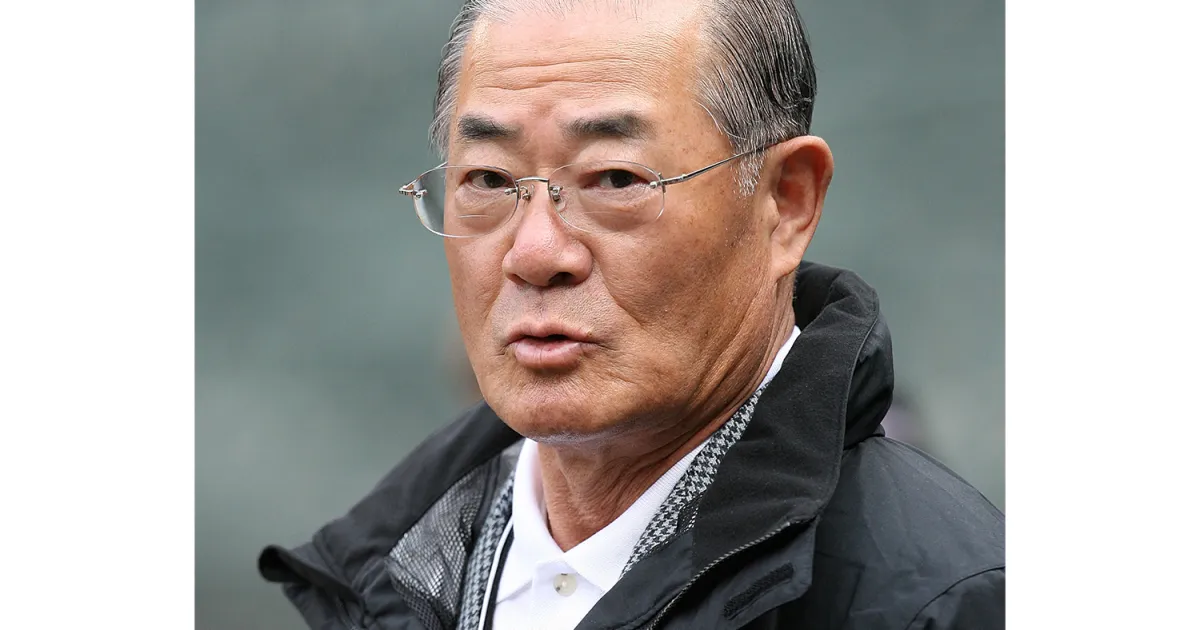 Older man wearing glasses and a black jacket, looking toward the camera.