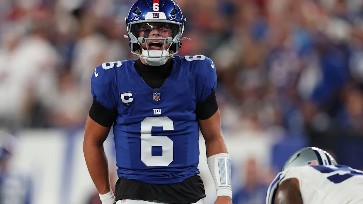 A New York Giants player wearing number 6 stands in uniform beside another player partly visible at right.