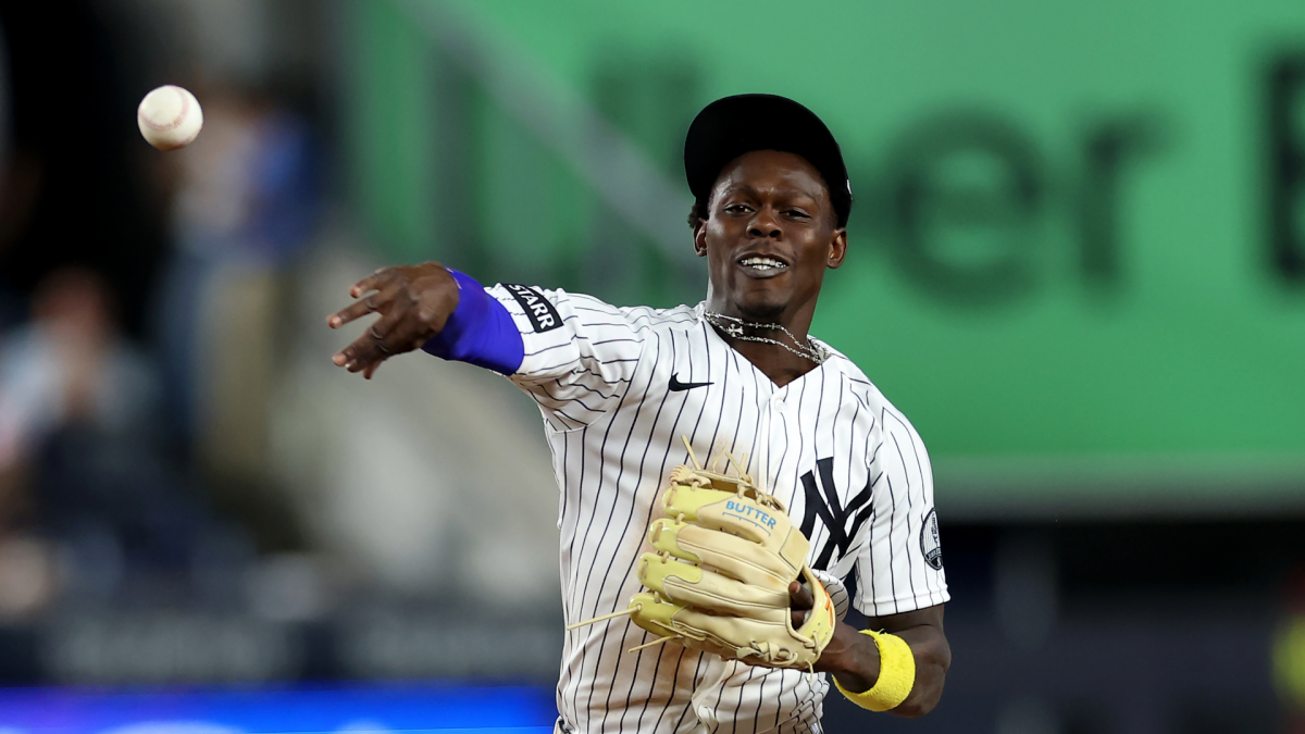 Yankees player in uniform throws a baseball while wearing a glove on the field