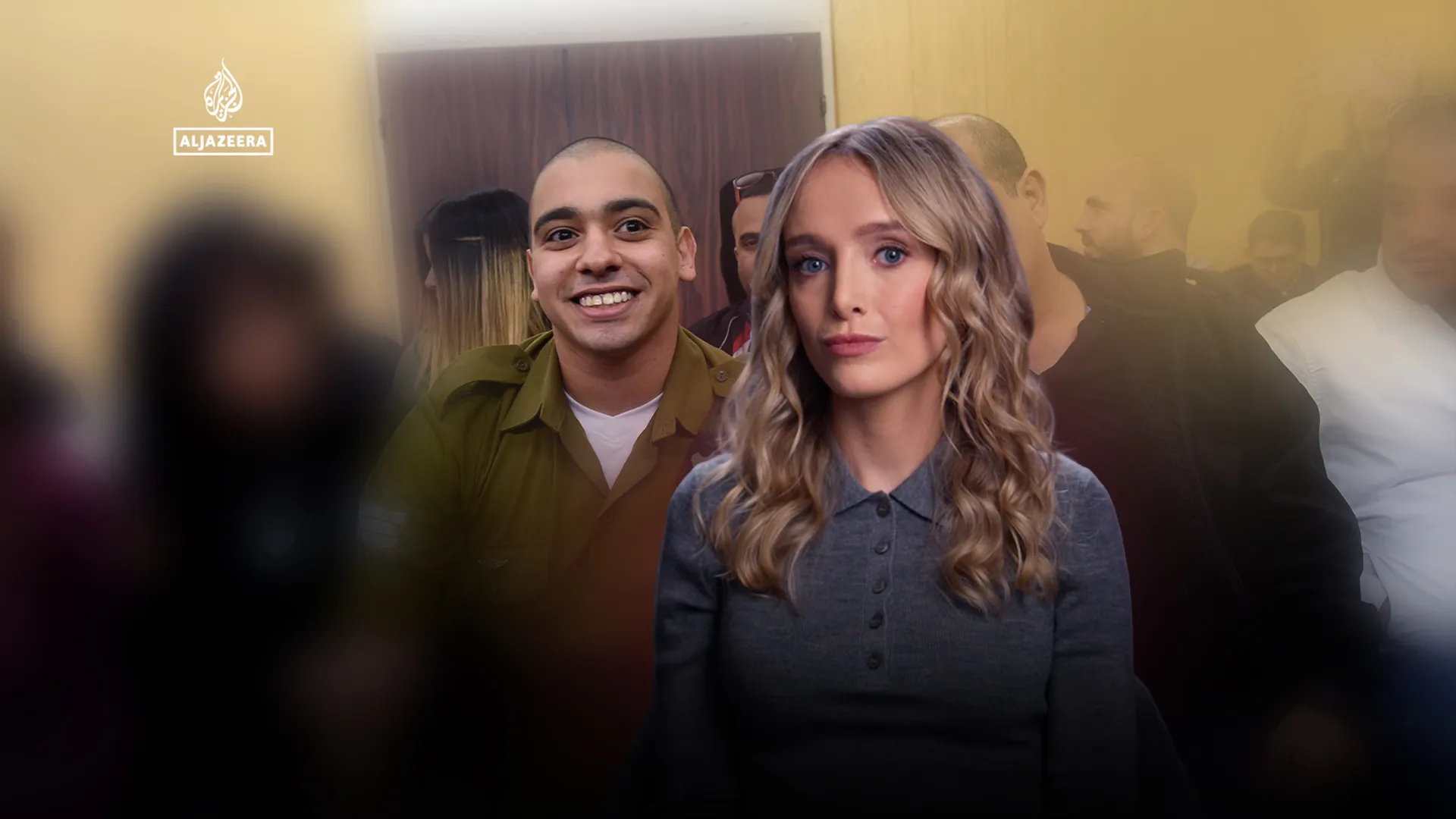 Smiling man and serious woman stand before a blurred crowd, with an Al Jazeera logo visible.