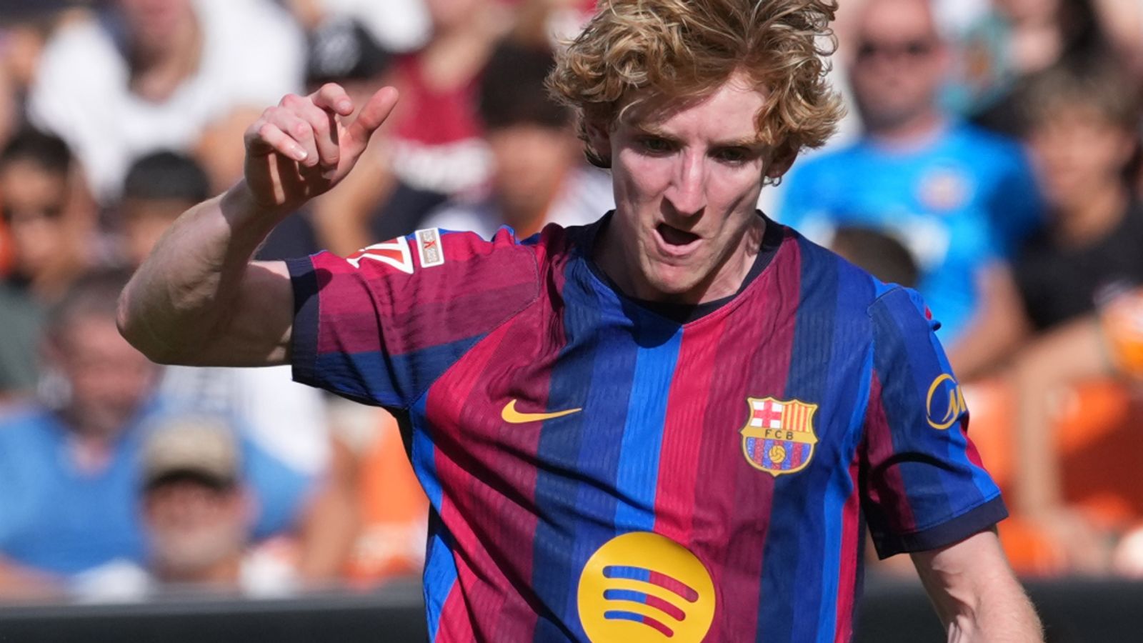 Barcelona footballer in striped jersey celebrates with raised fist during a match