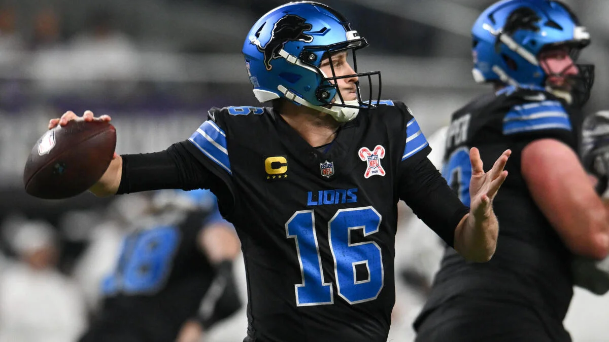 Detroit Lions player in a blue helmet and black number 16 jersey prepares to throw a football.