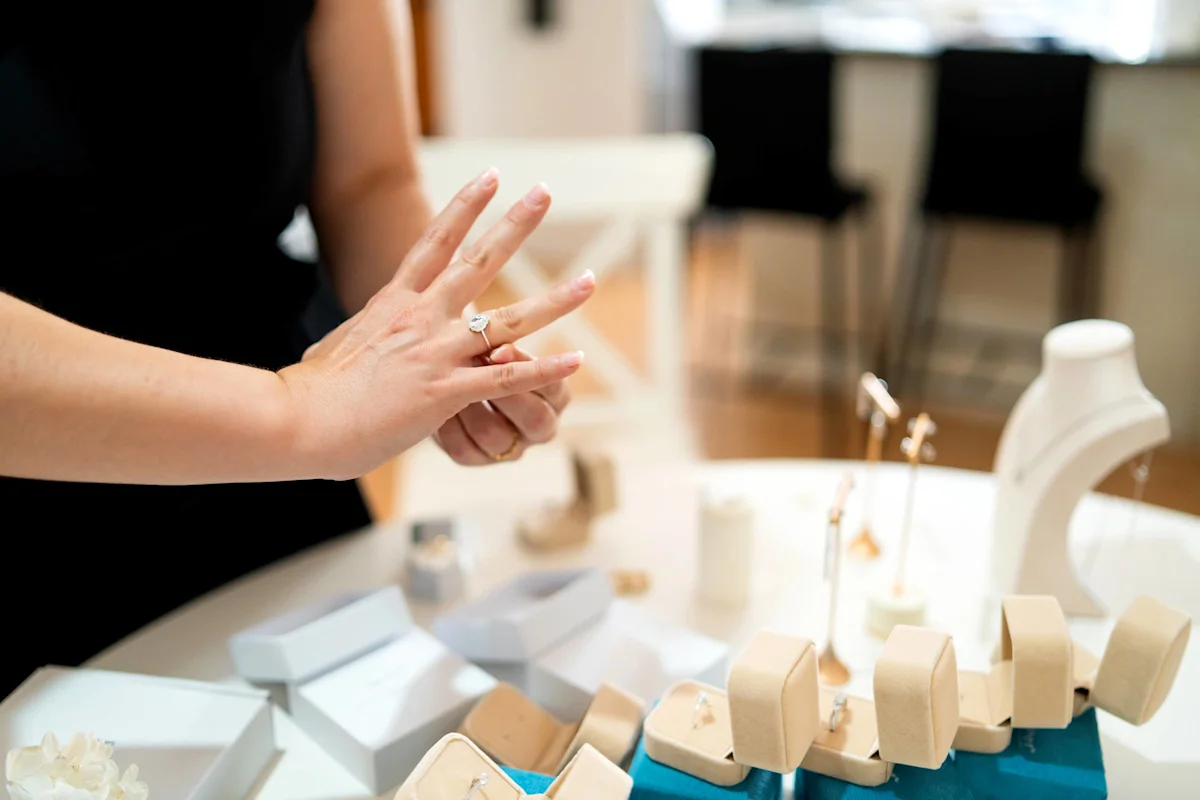 Person displays a ring while jewelry pieces and display stands sit on a counter.