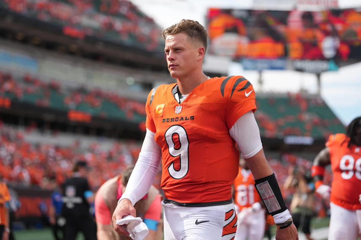 Football quarterback in orange Bengals uniform walking on field during a game