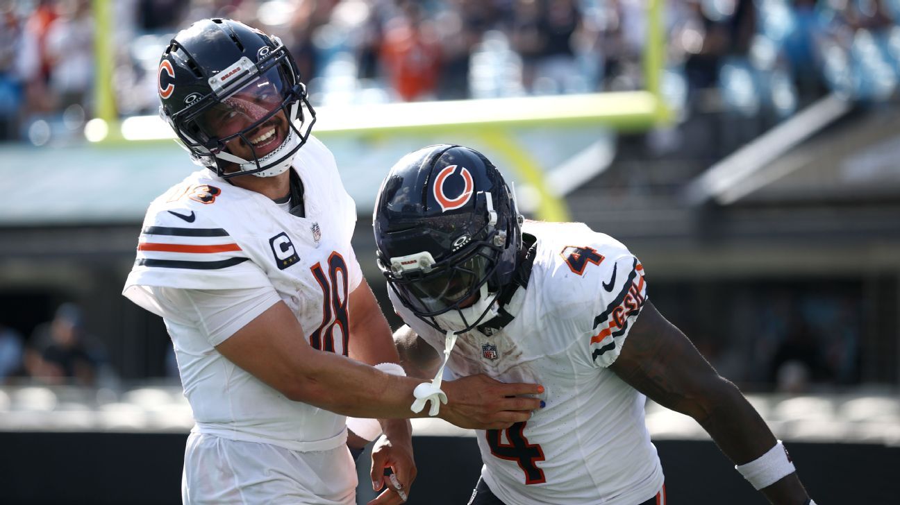 Two Chicago Bears football players celebrate during a game, wearing helmets and white uniforms.