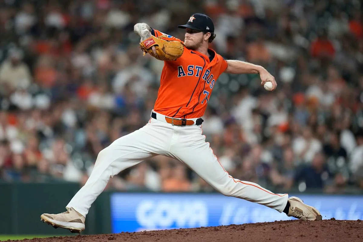 Houston Astros pitcher in an orange jersey delivers a pitch during a baseball game.