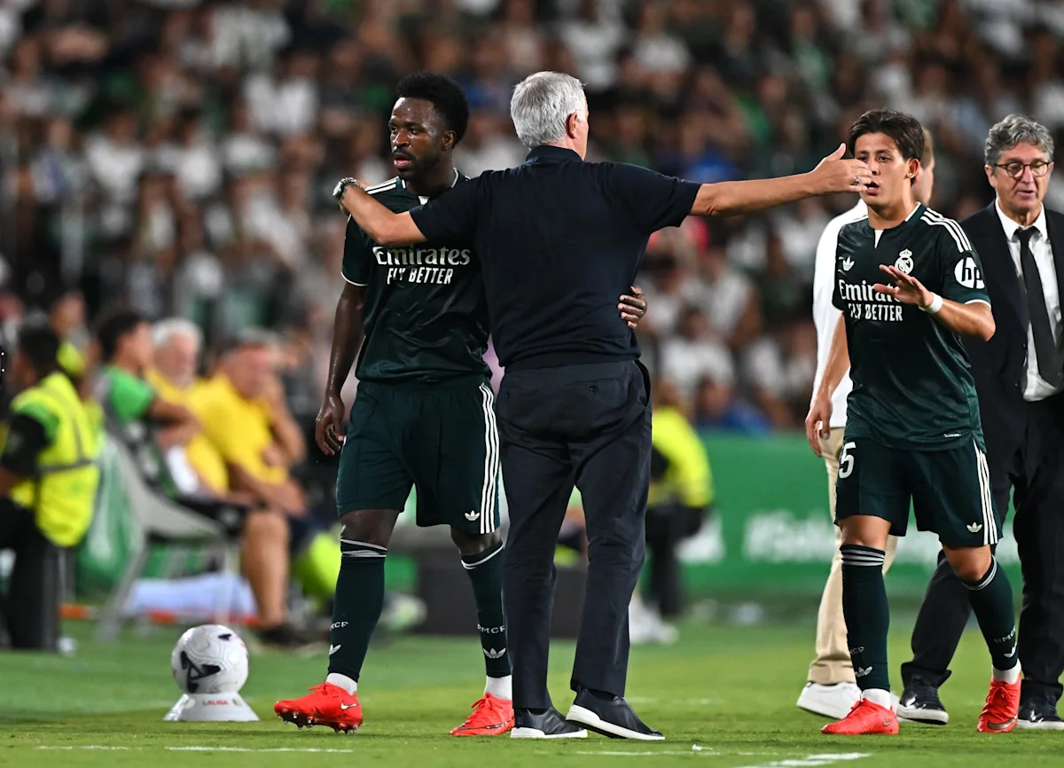 Football coach gestures between two Real Madrid players during a match on the pitch