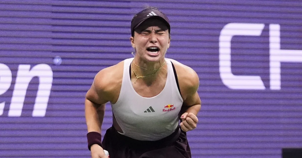 Emotional tennis player wearing a visor and white top reacts during a match.