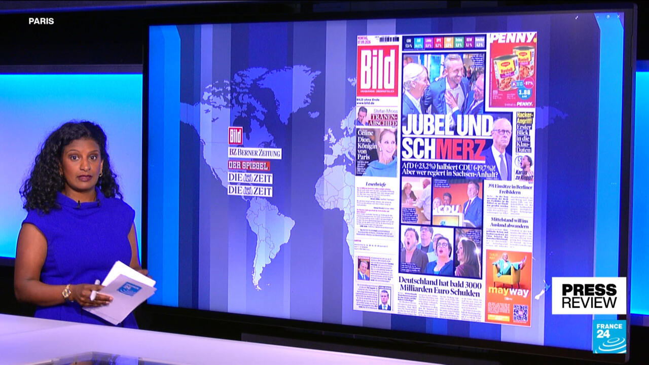 News presenter stands beside a screen displaying German newspaper front pages and a world map.