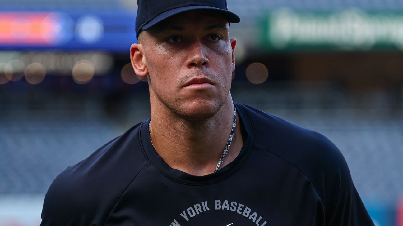 Baseball player in Yankees cap and black shirt looking seriously toward the camera