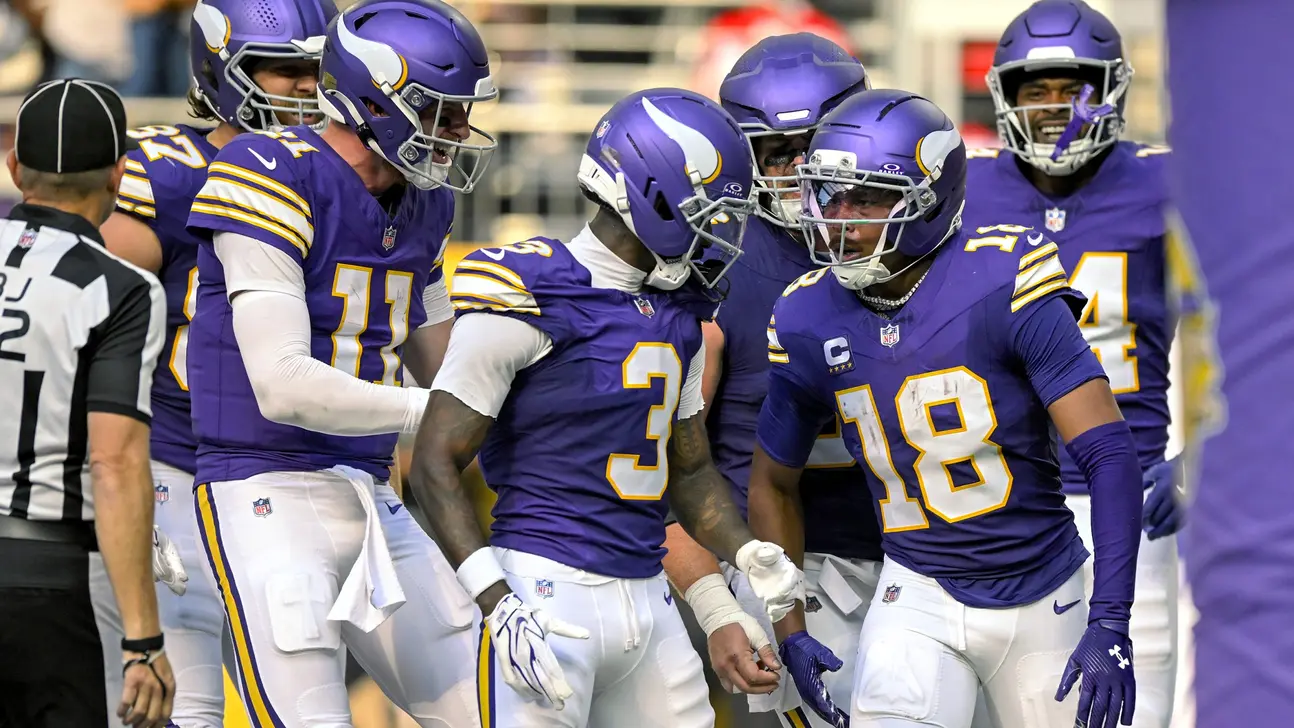 Minnesota Vikings football players in purple uniforms gather on the sideline during a game.