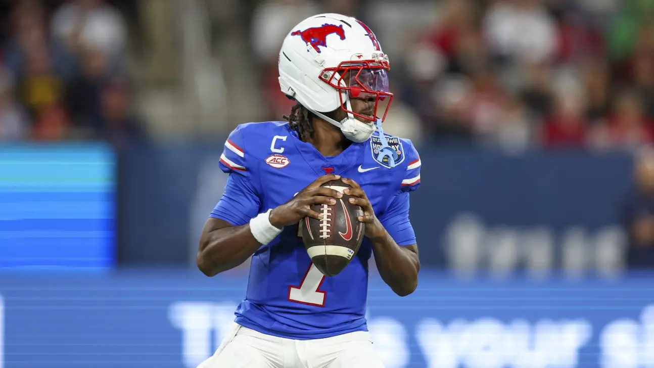 Football quarterback in blue jersey and white helmet holding the ball before a play