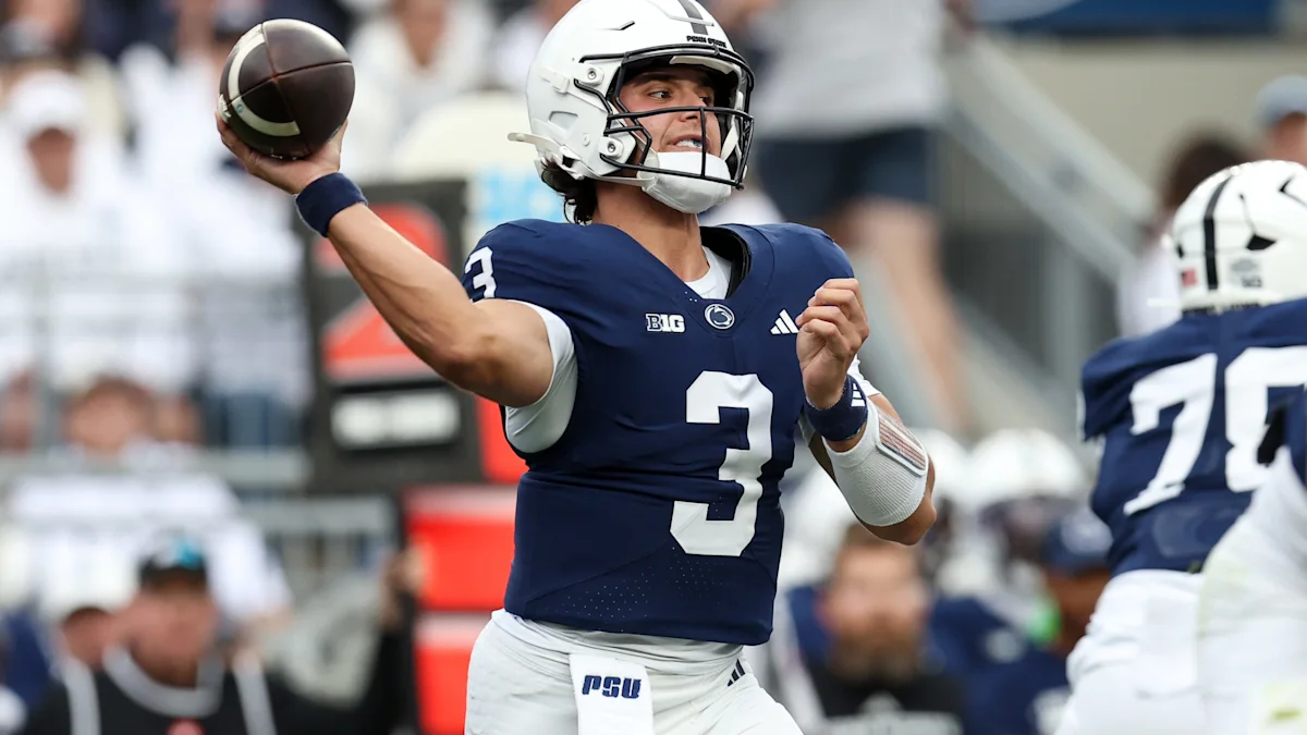 Penn State quarterback in a navy number three jersey throws a football during a game.