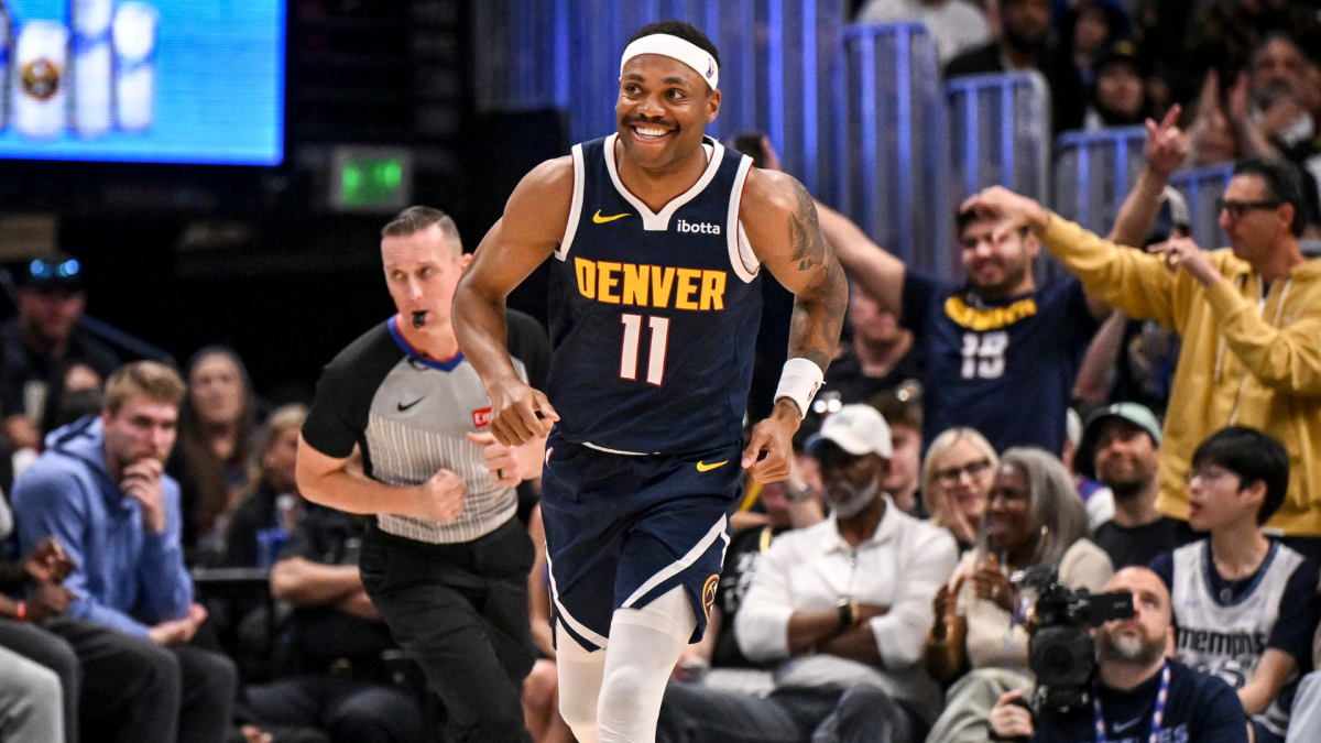 Denver basketball player wearing number 11 runs past a referee as fans cheer courtside.