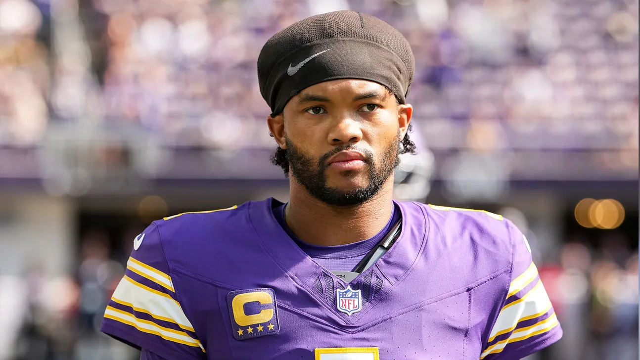 Football player in purple Vikings jersey and black head covering standing on the field