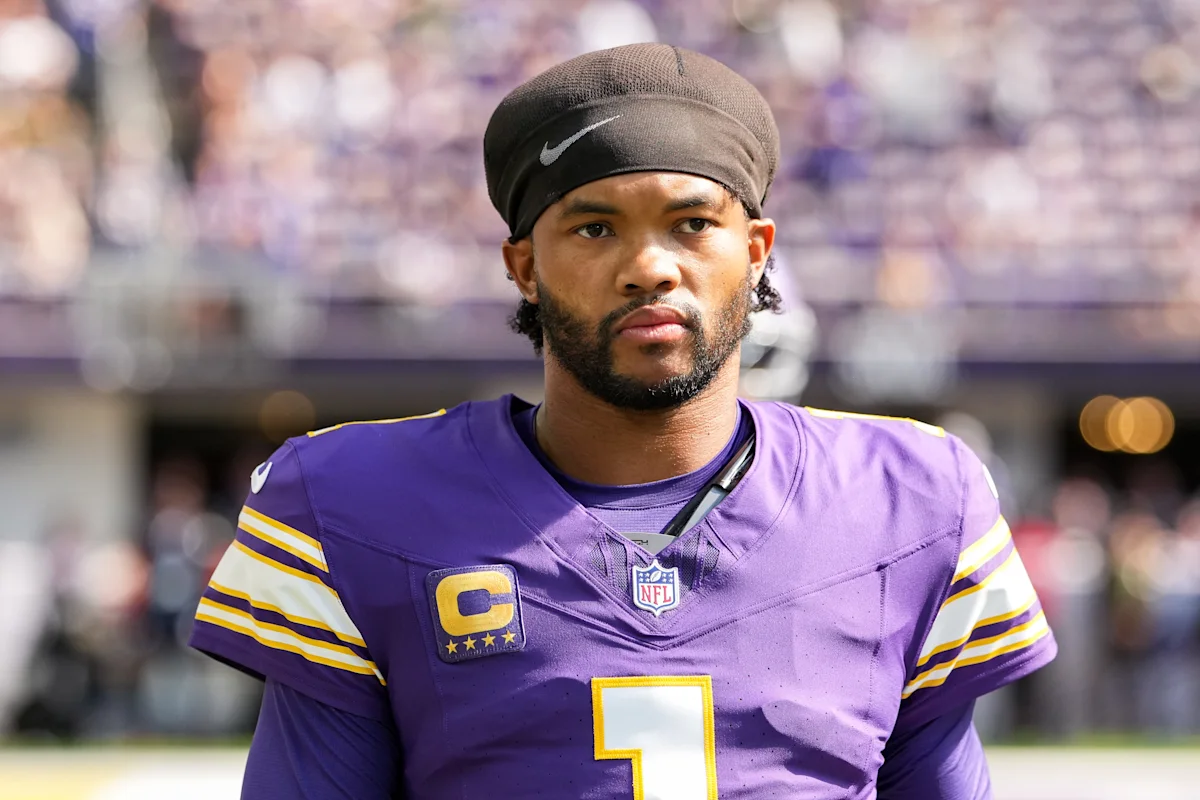 Football player in purple Vikings jersey and black headband standing on the field