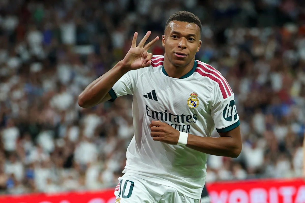 Footballer in white Real Madrid kit running and holding up four fingers during a match