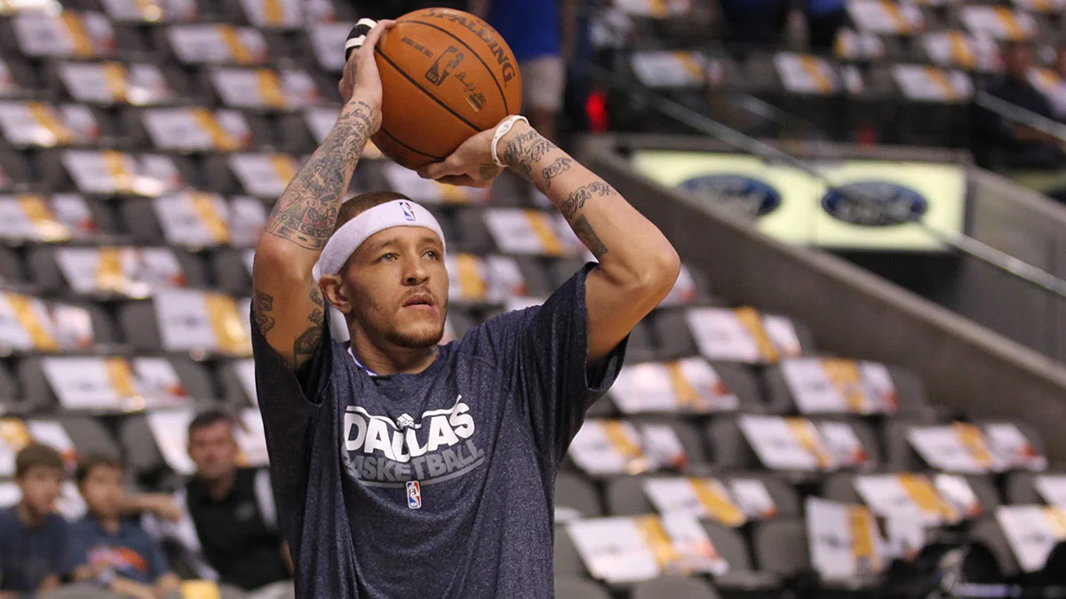 Basketball player in a Dallas shirt raises the ball overhead during a practice session