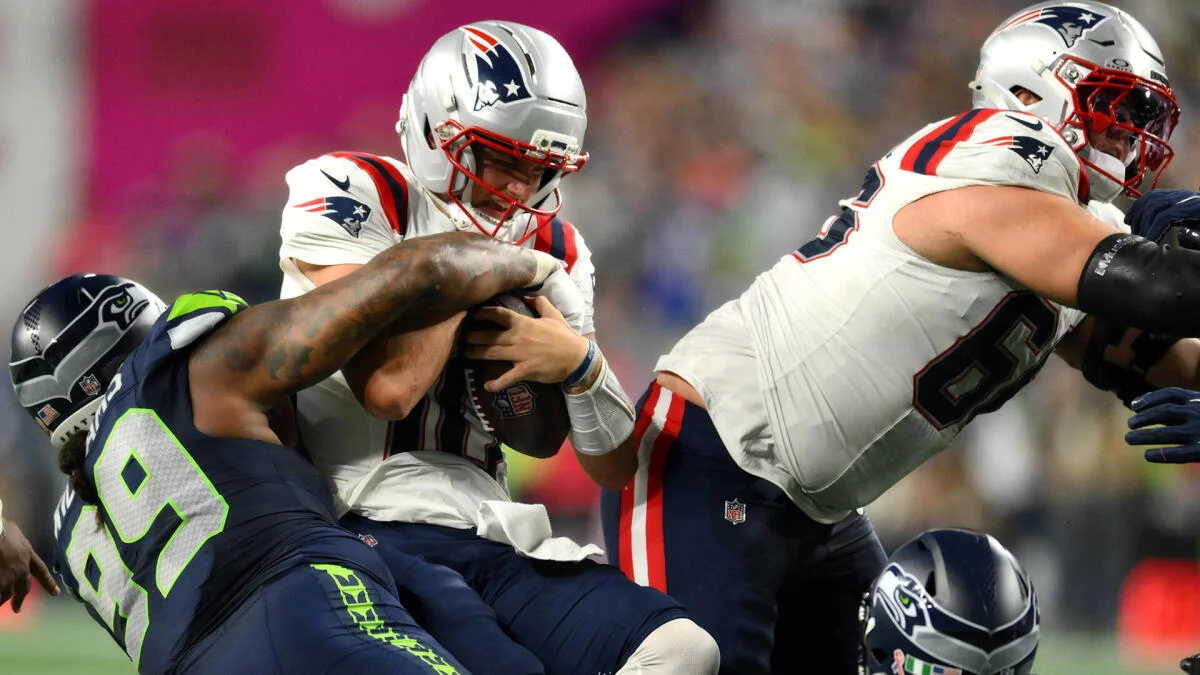 NFL players in Patriots and Seahawks uniforms collide during a close-up football play