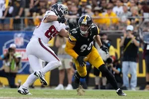 Football players in black and gold and white uniforms compete during a game