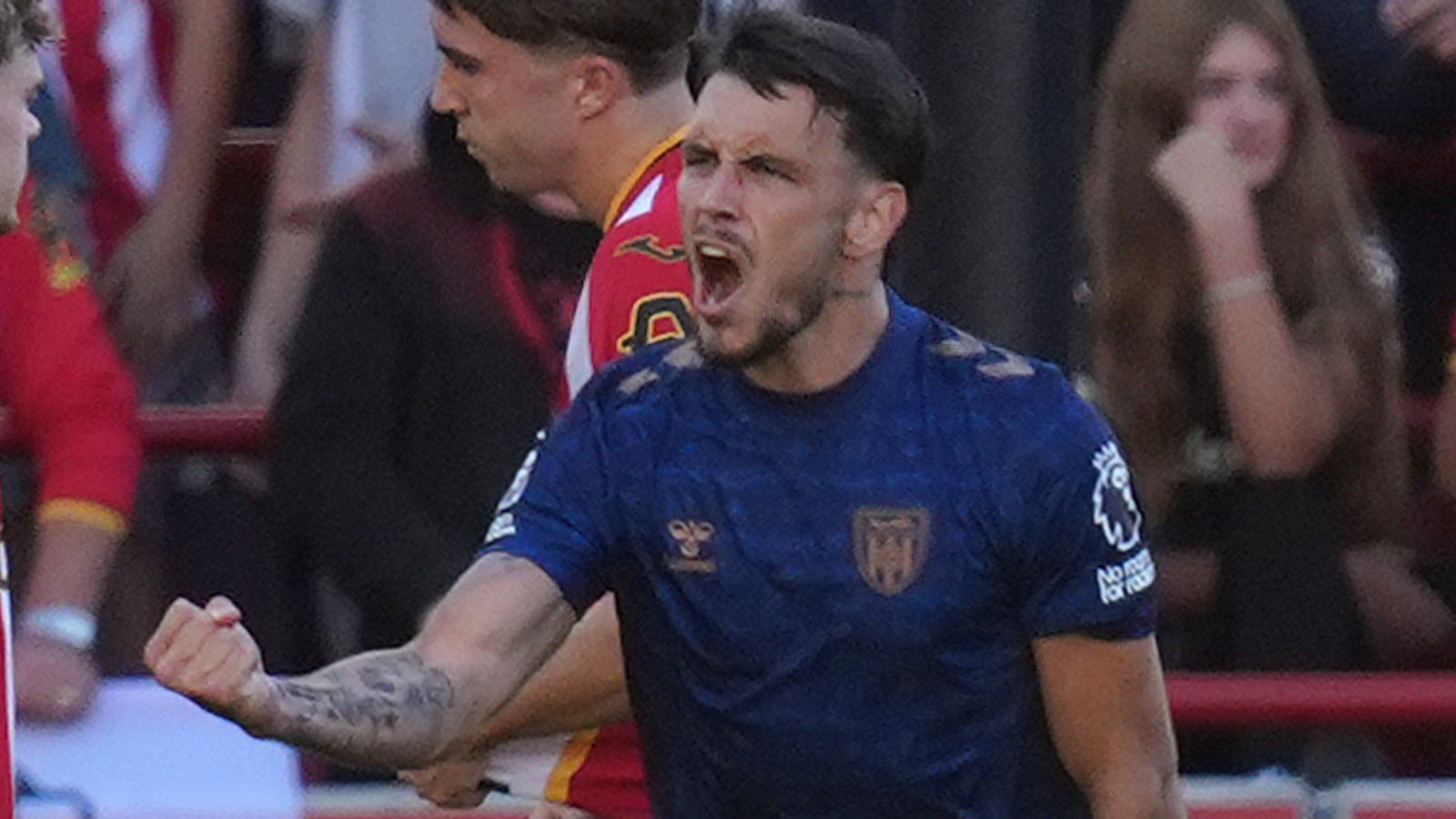 Footballer in blue shirt shouting and clenching his fist during a match