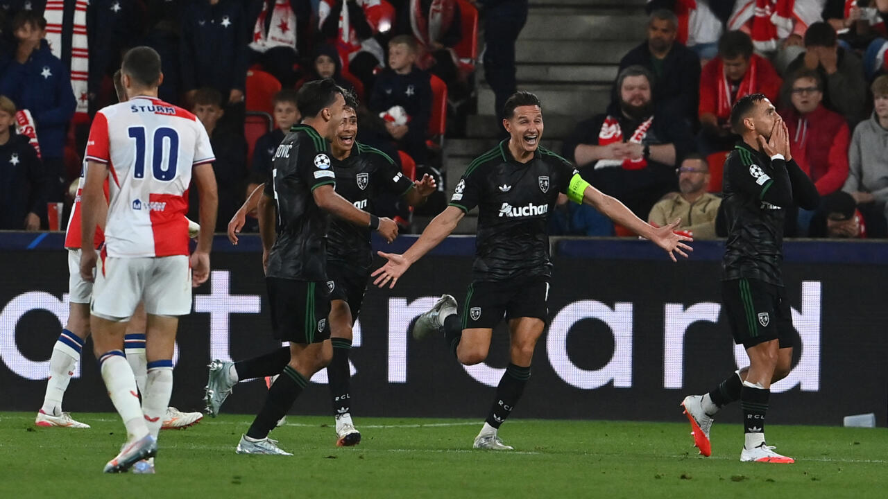 Lens players celebrate while opponents in white shirts walk away during a football match