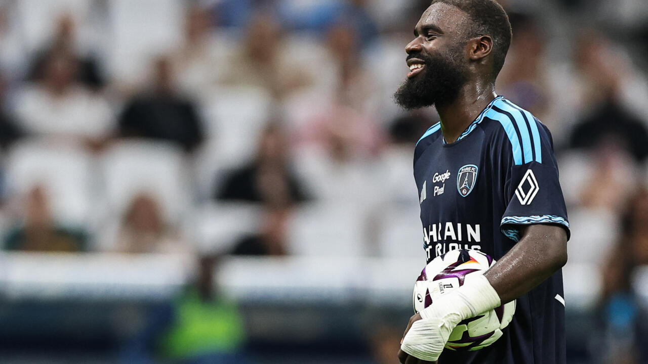 Paris FC goalkeeper smiling while holding a football during a Ligue 1 match