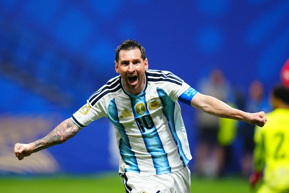 Argentine footballer in striped jersey celebrating with arms outstretched during a match