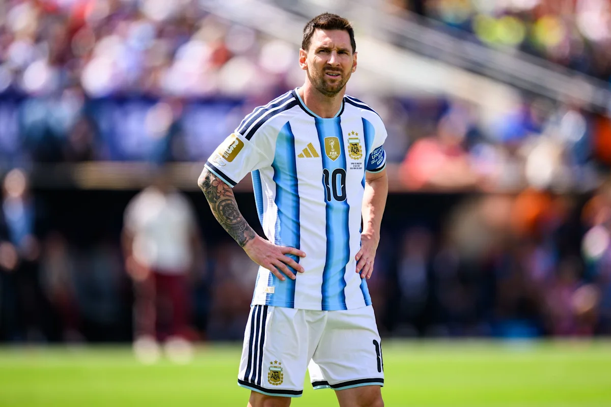 Footballer in Argentina’s striped jersey standing on the pitch with hands on hips