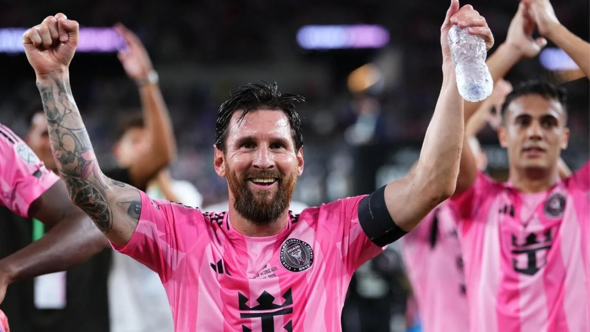 Lionel Messi raises both arms in celebration while wearing Inter Miami’s pink jersey.