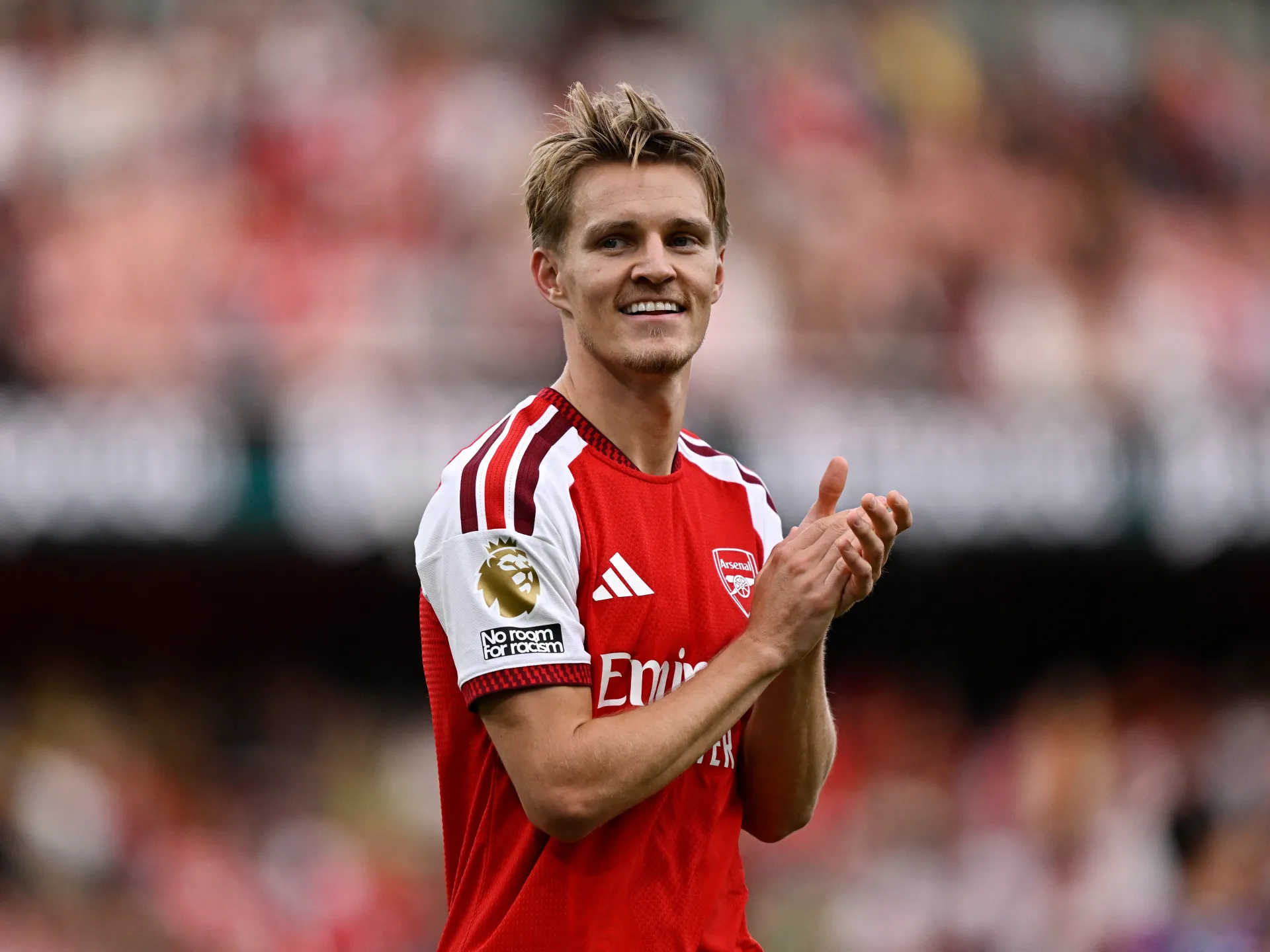 Arsenal footballer in red and white kit claps during a match