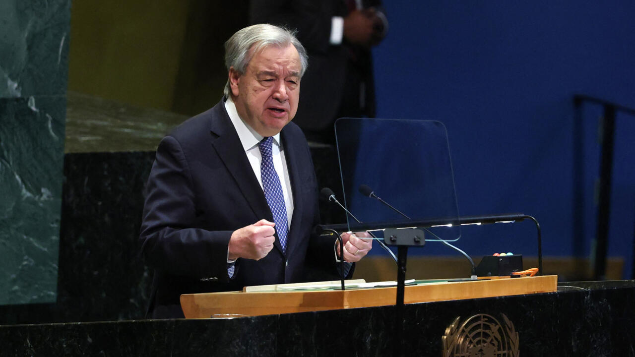 Man in suit speaking at a lectern with microphones and a transparent teleprompter