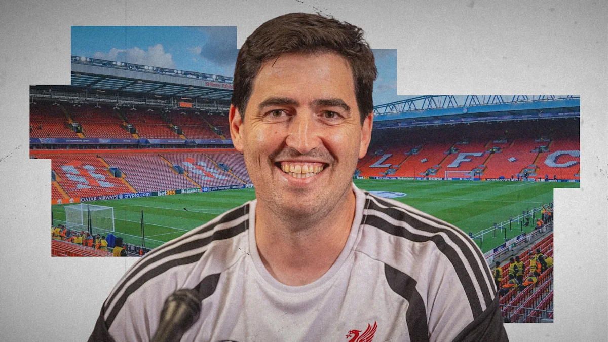 Smiling man in a Liverpool football shirt pictured before a stadium backdrop with a microphone