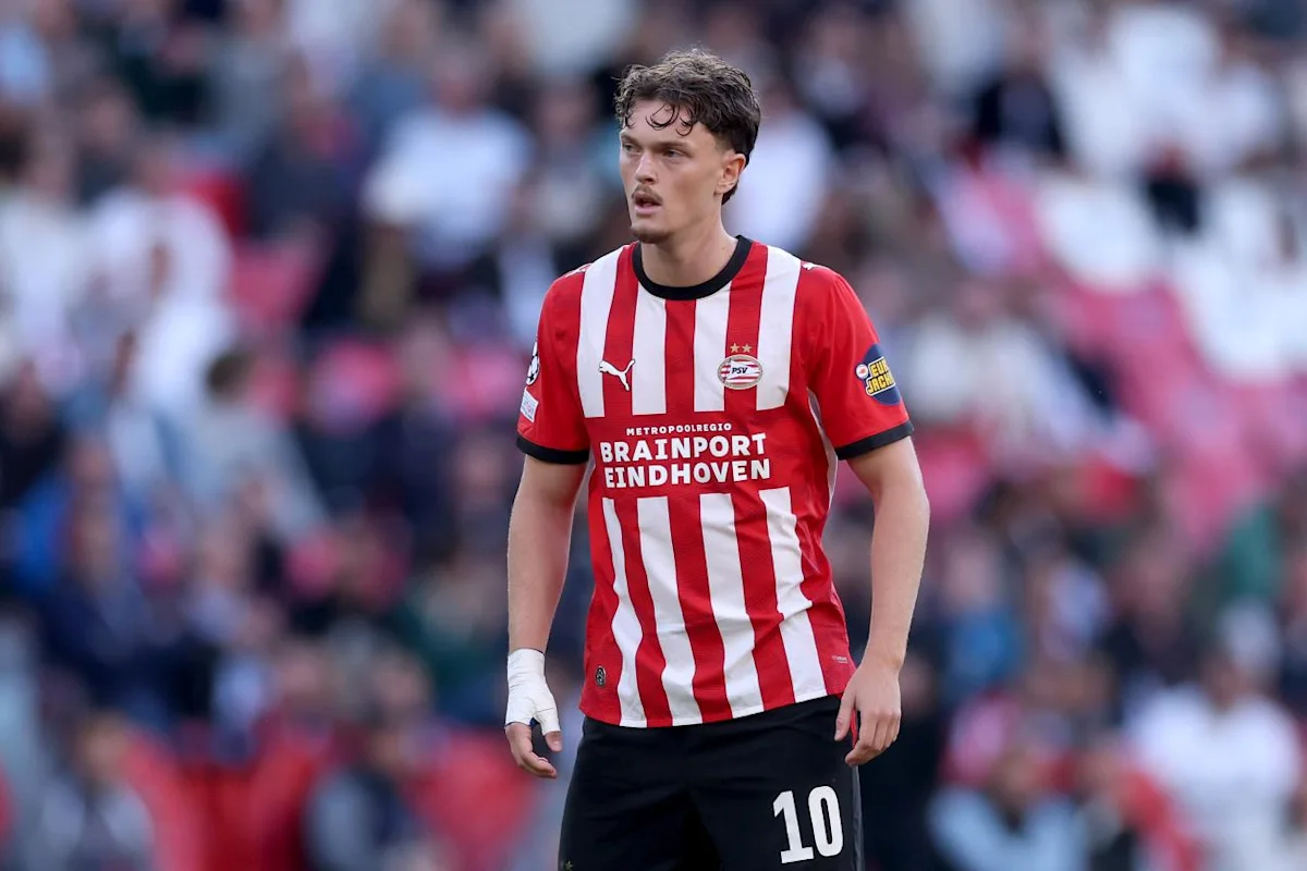 Footballer in PSV Eindhoven red-and-white striped kit standing on the pitch during a match