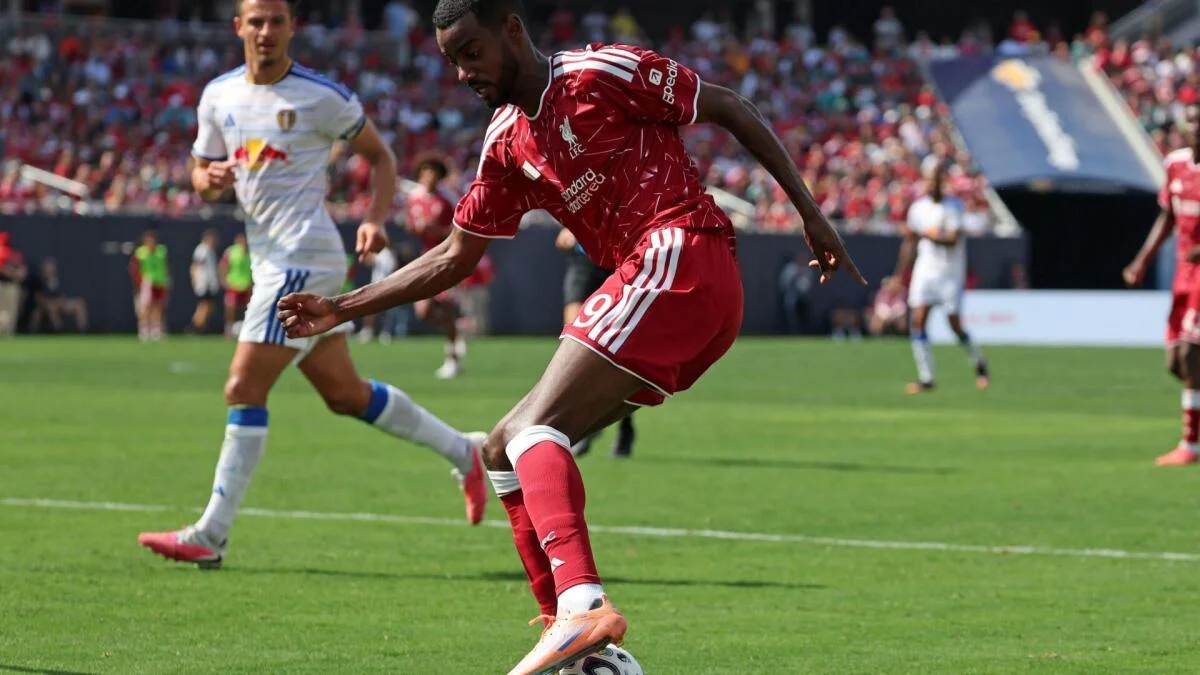 Liverpool player in red strikes the ball during a soccer match as opponents chase