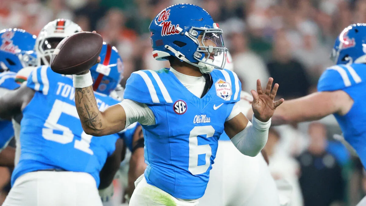 Ole Miss quarterback in blue uniform throws a football during a college football game.