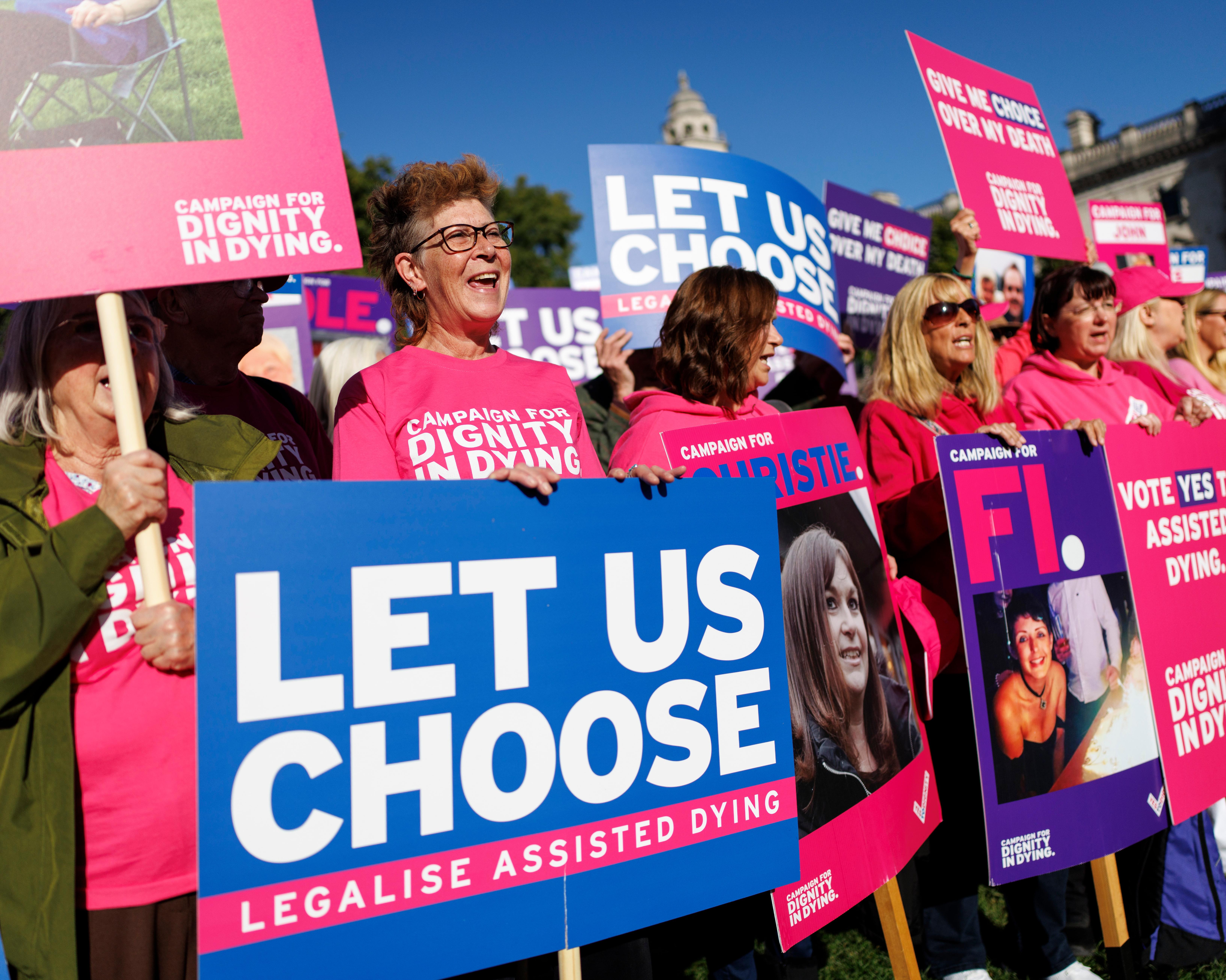 Crowd holding colourful signs supporting legalised assisted dying at a public demonstration