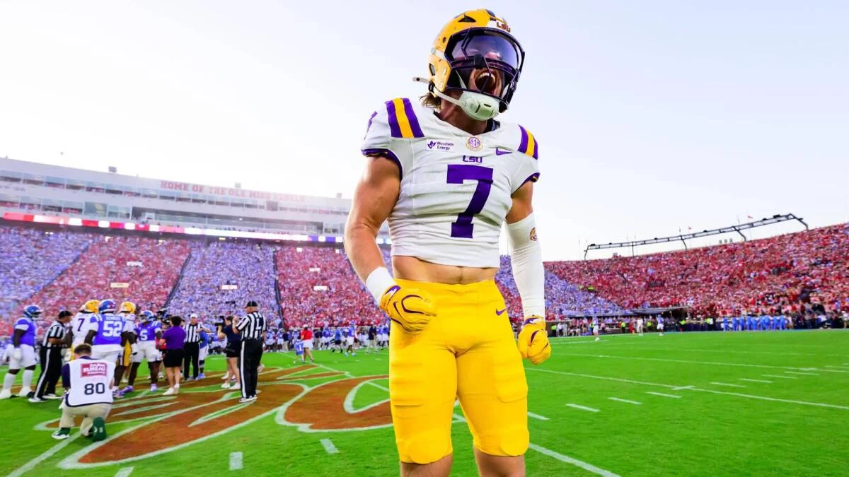 LSU football player wearing number 7 stands on the field in a crowded stadium.