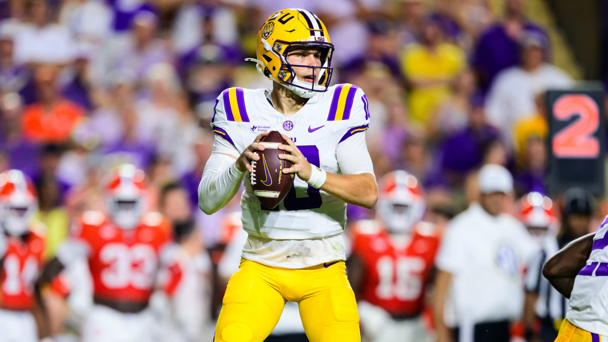 Football quarterback in LSU uniform grips the ball while preparing to pass during a game