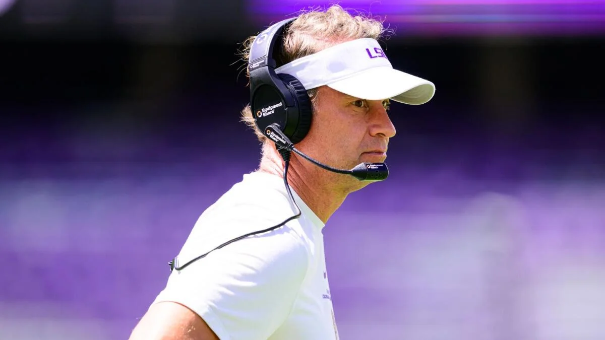 Football coach wearing a visor and headset on the sideline