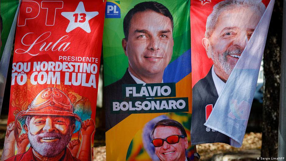 Colorful Brazilian campaign banners show portraits of Lula and Bolsonaro alongside political slogans.