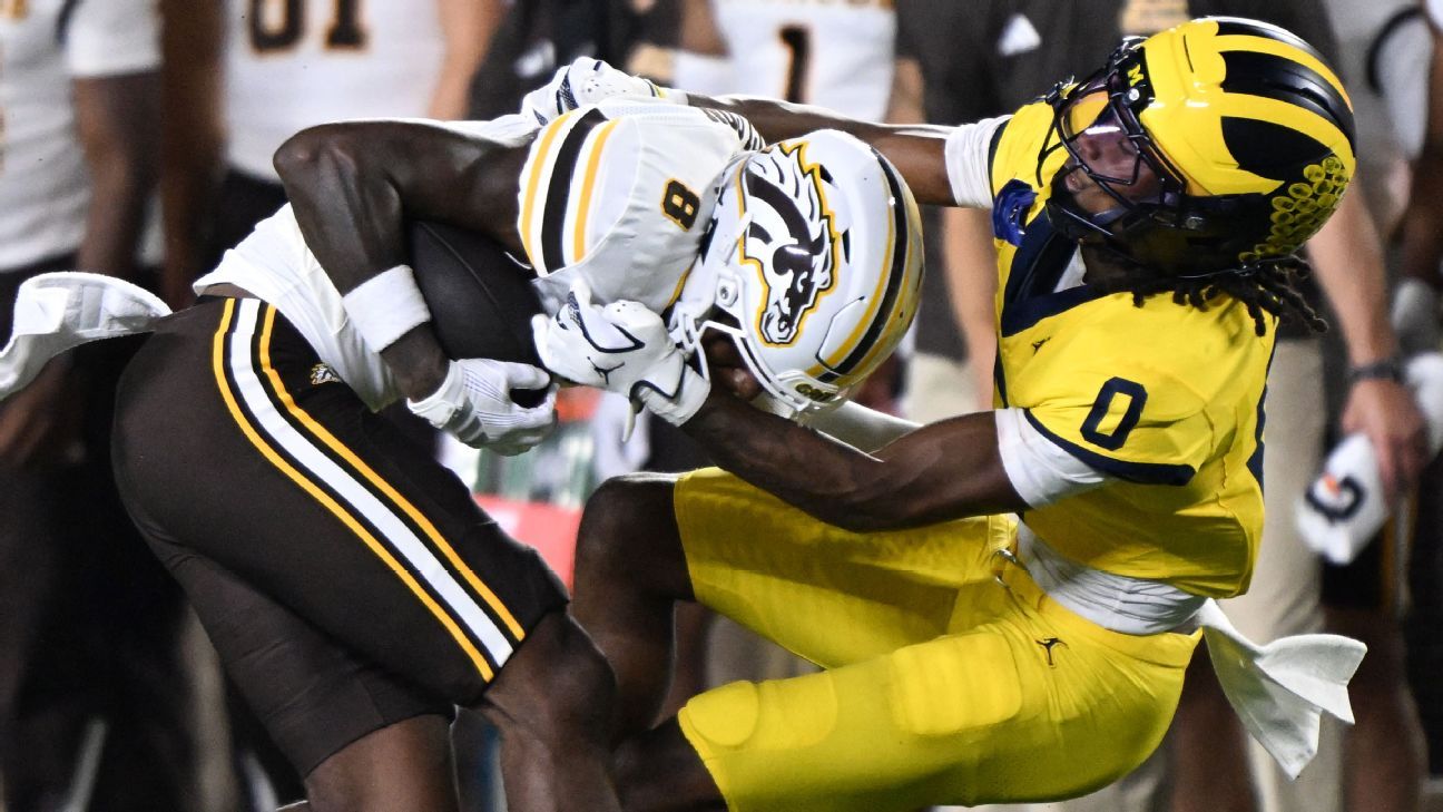 Football players in yellow and white uniforms collide during a tackle near the sideline.