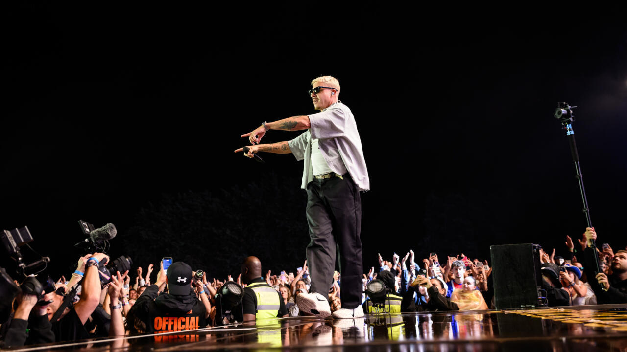 Male performer points toward a cheering crowd while standing at the edge of a concert stage