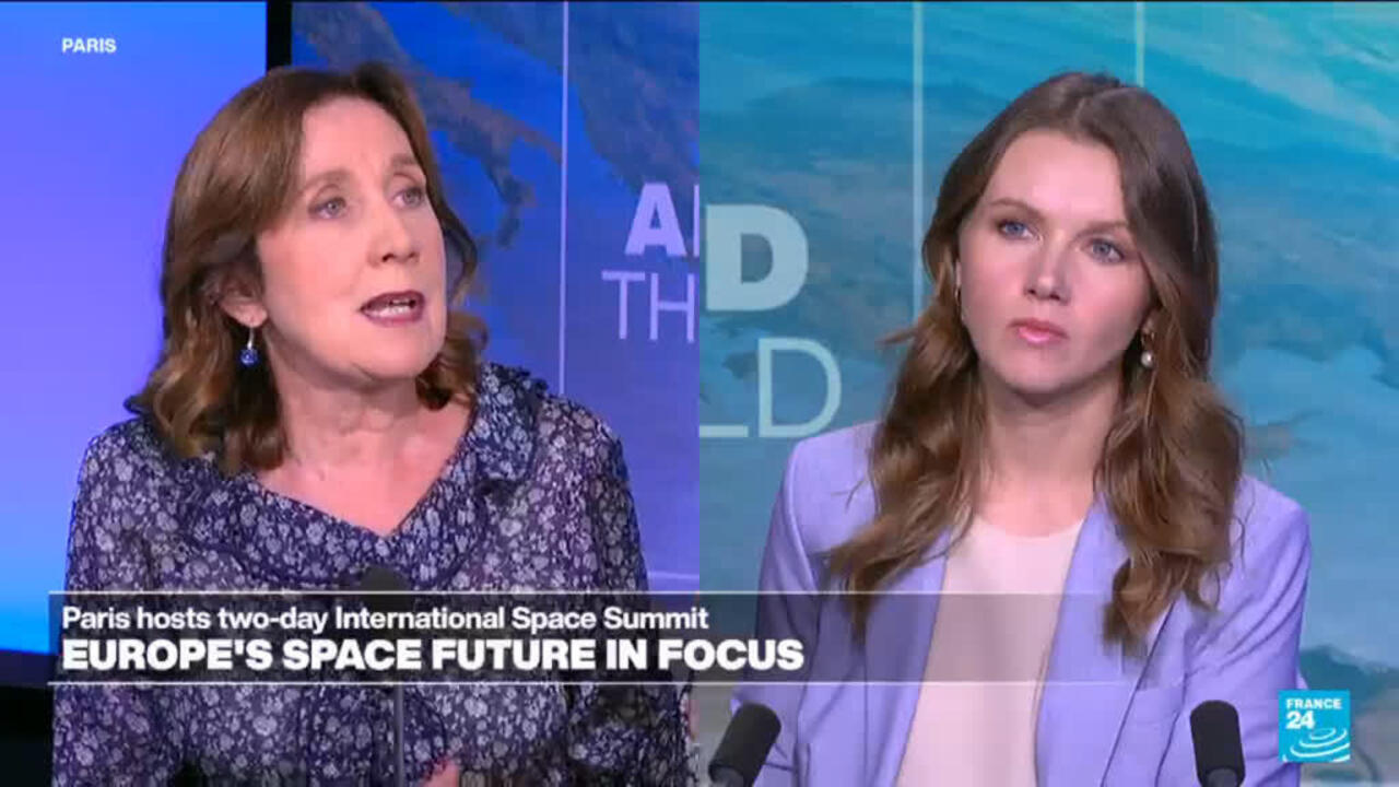Two women discuss European space policy during a televised interview, with microphones and a summit graphic behind them.