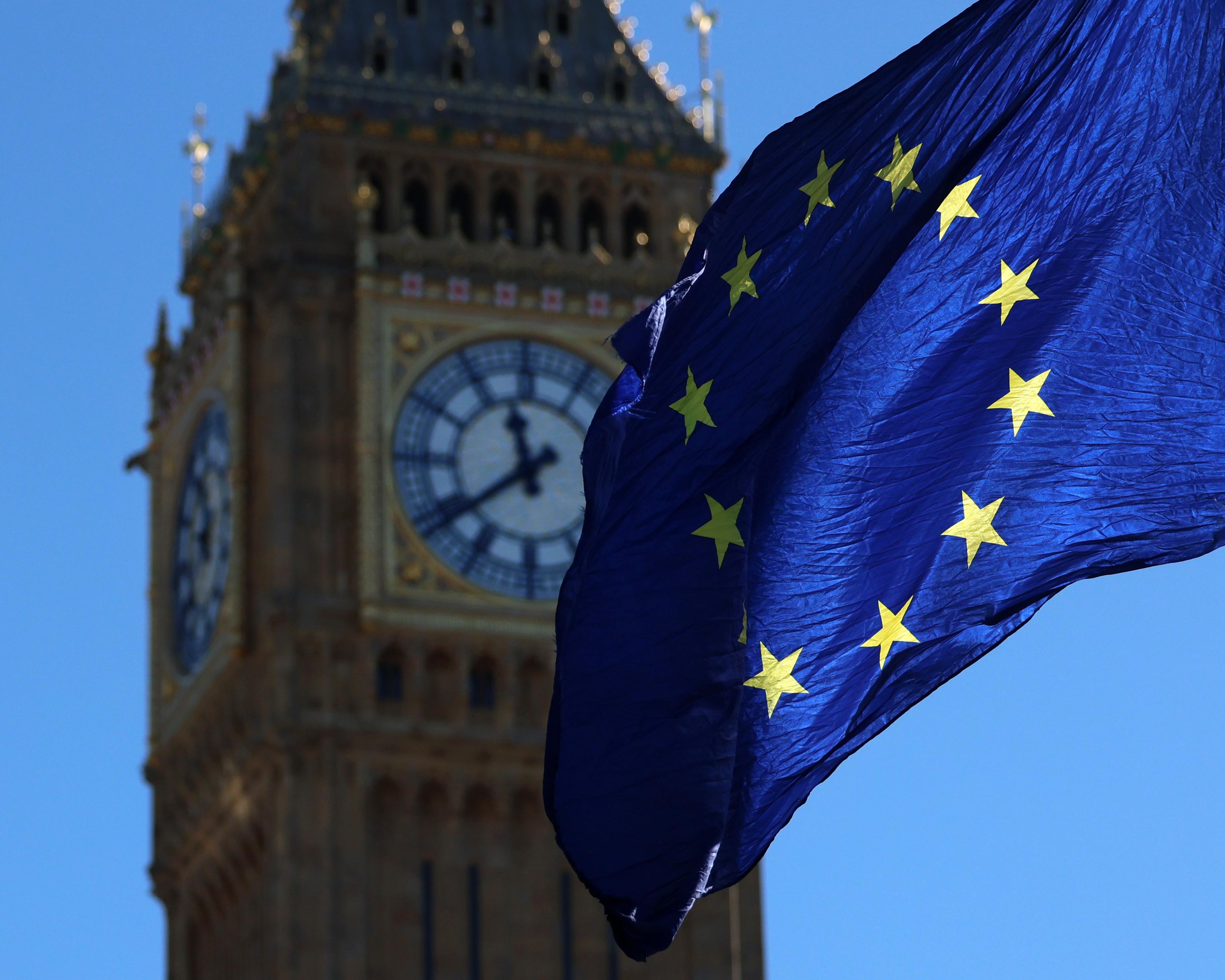 European Union flag billowing in front of a clock tower resembling London’s Big Ben