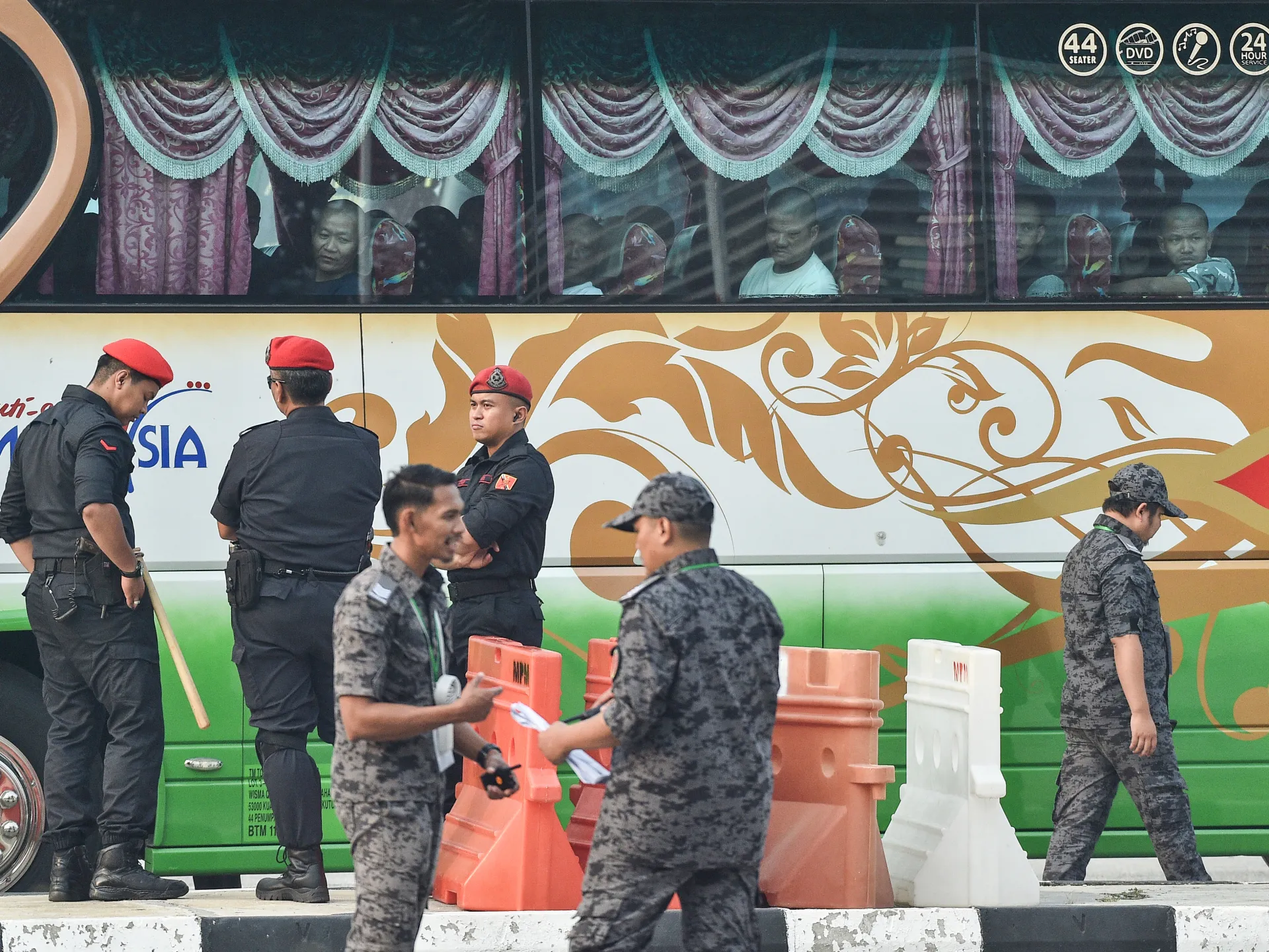 Uniformed officers stand beside a bus with passengers visible behind curtained windows.