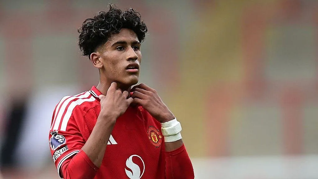 Manchester United footballer in red jersey adjusting his shirt collar during a match