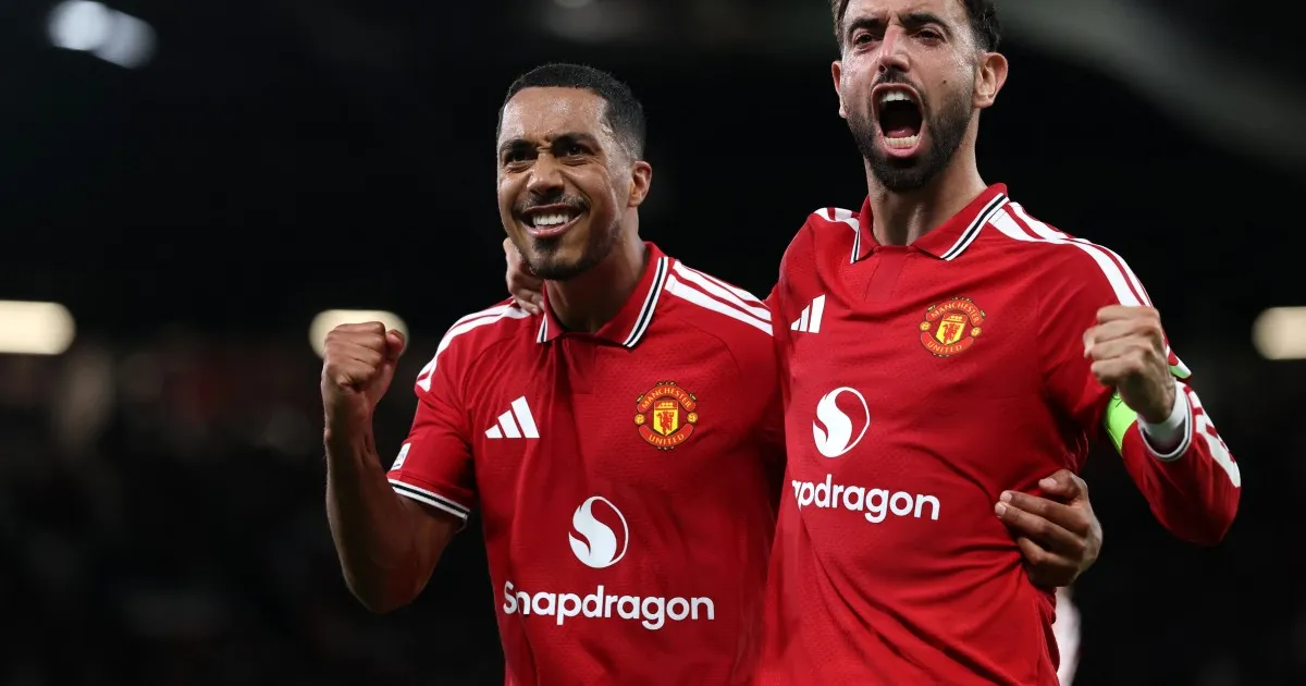 Two Manchester United players in red jerseys celebrate with raised fists during a match