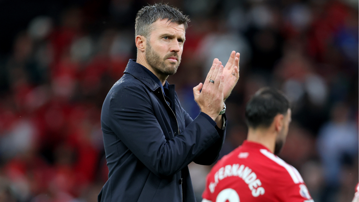 Football coach applauds on the touchline as a Manchester United player stands in the foreground