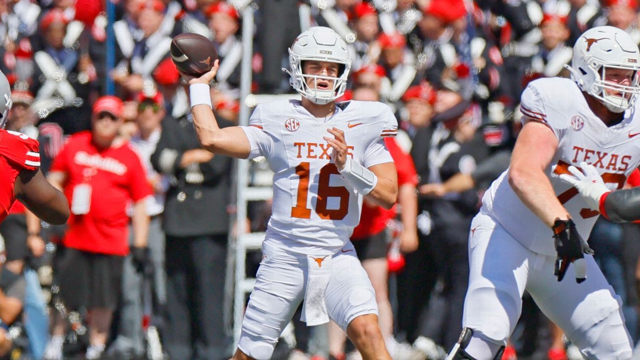 Texas quarterback in white uniform throws a football as teammates block amid a crowded stadium.
